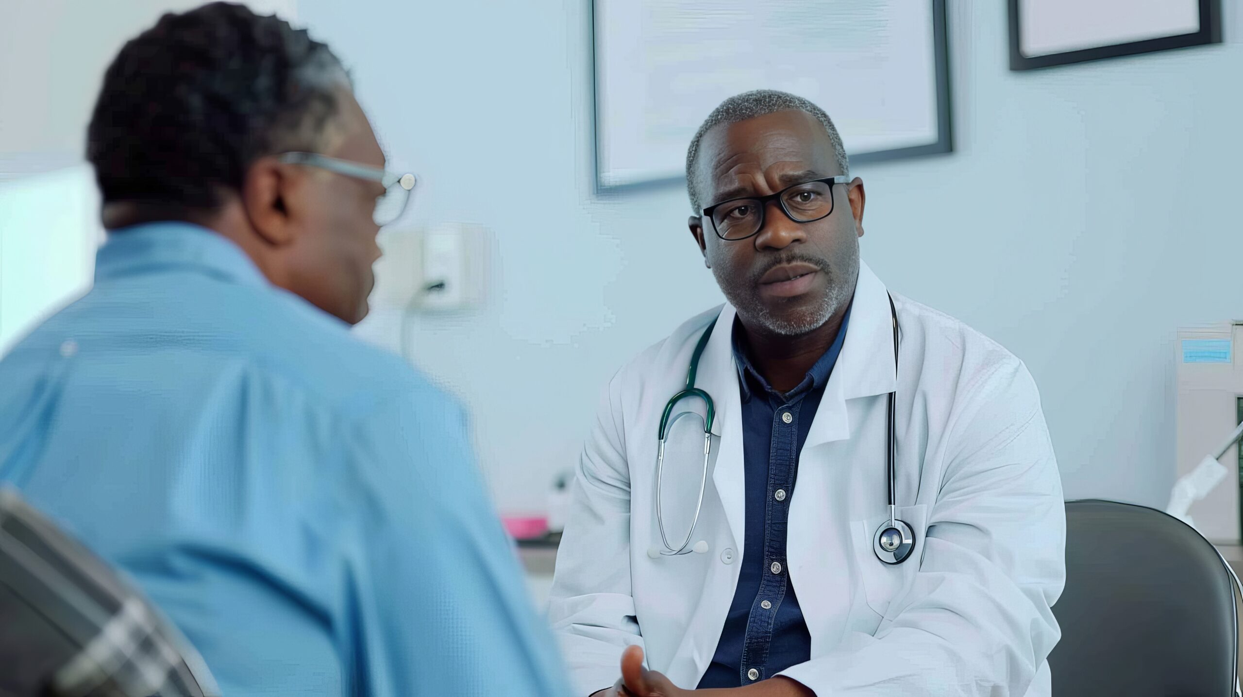 hispanic doctor consulting with black elderly patient bright clinic scaled